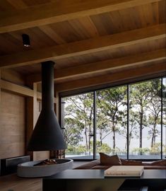 an open living room with large windows and wood ceilinging, along with modern furniture