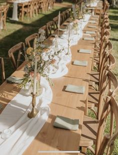 a long table set up with place settings and flowers in vases on the tables