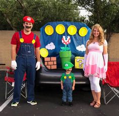 a man and woman standing next to a child in front of a car with mario bros on it