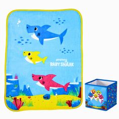 the baby shark blanket is next to it's box and its cover has fish on it