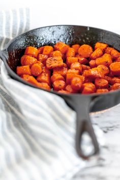 a skillet filled with cooked carrots on top of a white and gray towel