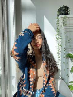 a woman sitting on top of a white couch next to a plant filled window sill