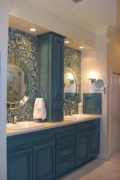 a bathroom with blue cabinets and mirrors on the wall, along with a white towel hanging in front of it