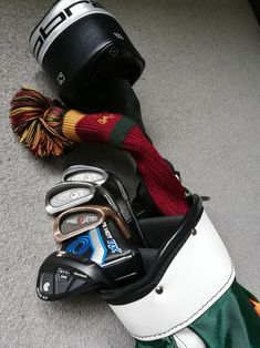 the golf bag is next to several other items on the floor, including a ball and driver's hat