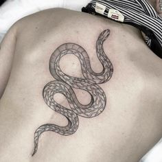 a tattoo on the back of a man's stomach shows a black and white snake