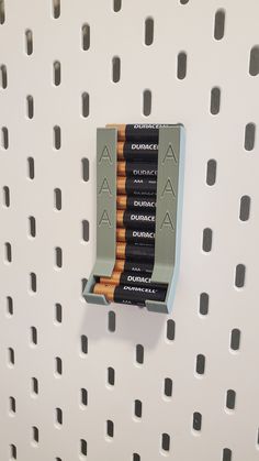 four aa batteries are placed on a perfored wall