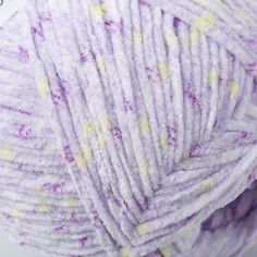 a ball of yarn with yellow and purple speckles on the top, sitting in front of a white background