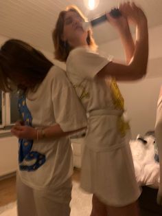 two women standing in a living room brushing their hair