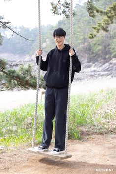 a young man standing on a rope swing