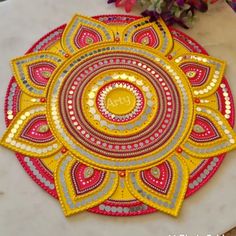 a yellow and red doily sitting on top of a white counter next to flowers