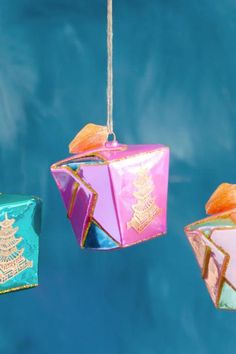 three colorful ornaments hanging from strings in the shape of an ornament on a blue background