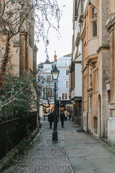 people are walking down the street in an old european town with cobblestone streets