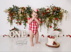 a baby girl standing in front of a cake