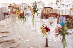 there are many vases with flowers in them on the table at this wedding reception