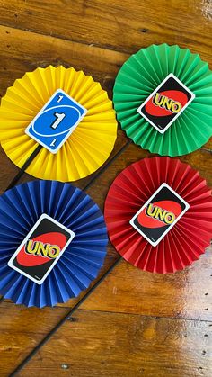 four different colored paper fans sitting on top of a wooden floor