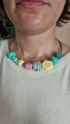 a close up of a person wearing a necklace with multi colored beads on the neck