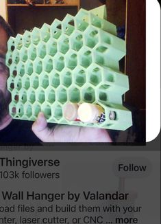 a man holding up a cell phone in front of an egg carton