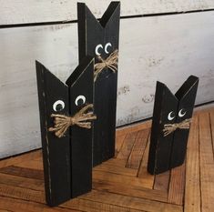 two black wooden sticks with eyes and noses tied to them, sitting on a wood floor