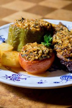 a white plate topped with stuffed peppers and other food on top of a wooden table