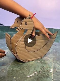 someone is holding an origami duck in the shape of a boat on top of water