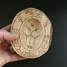 a hand holding a wooden plate with designs on it