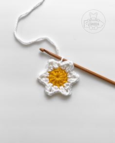 the crochet flower is next to a knitting needle on a white tablecloth