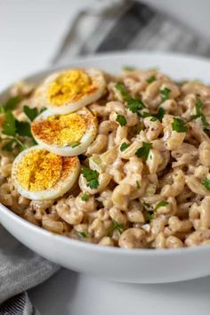 a bowl filled with macaroni salad topped with hard boiled eggs and parsley