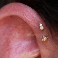 a woman's ear with two small diamond studs