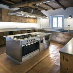 an empty kitchen with stainless steel appliances and wood flooring on the walls is pictured in this image