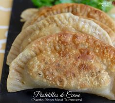 three pieces of empanada sitting on top of a black plate next to lettuce