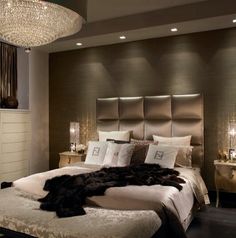 a large bed sitting under a chandelier next to a night stand in a bedroom