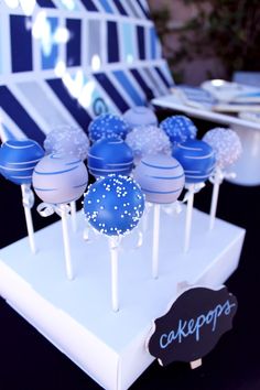 blue cake pops are sitting on top of a white stand with black and white stripes