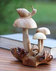 a wooden sculpture of three mushrooms on a table with a book in the back ground