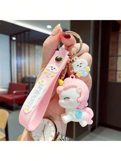 a person holding two keychains in their hand, one with a bear and unicorn on it