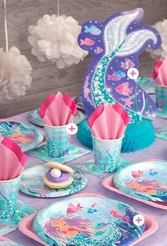 a table set with plates, cups and napkins for a little mermaid birthday party