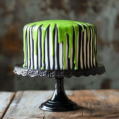 a cake with green icing and black stripes on it sitting on top of a wooden table