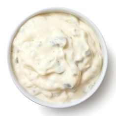 a white bowl filled with cream sauce on top of a table