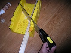 a person holding a knife over a yellow box with holes in it on a wooden floor