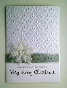 a christmas card with a white flower on the front and green ribbon at the bottom