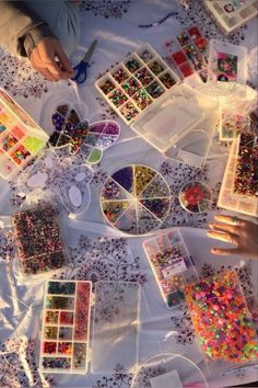 the table is covered with lots of beads and other crafting supplies, including nail polish