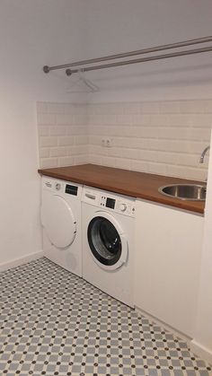 a washer and dryer in a small room with tile flooring on the walls