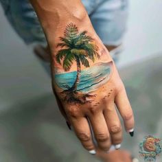 a palm tree tattoo on the left hand is painted with blue water and white sand