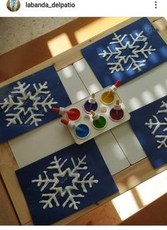 snowflakes and paint are sitting on top of a table with blue squares