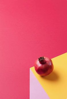 an apple sitting on top of a yellow and pink surface