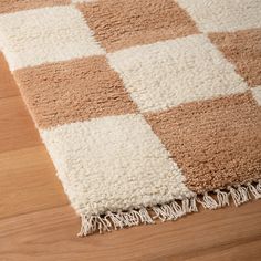 a brown and white checkered rug on top of a wooden floor