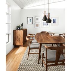 a dining room table with chairs and pictures on the wall above it, along with an area rug