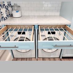 two washers and dryer in a kitchen with blue cabinets, white counter tops and tile backsplash