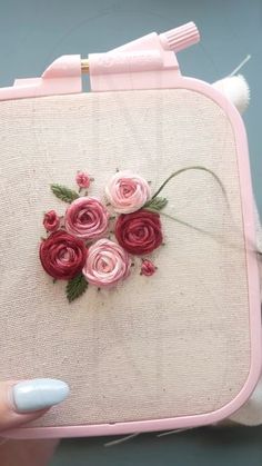 a hand holding a pink purse with flowers on it