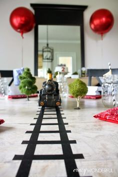 a toy train is going down the track in front of some red balloons and other decorations