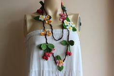 a white dress with flowers and leaves on the neck is displayed in front of a mannequin